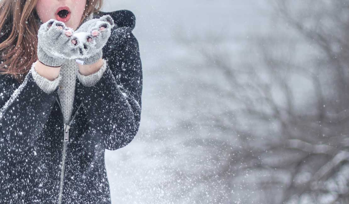 Girl playing in snow, blowing snow out of her hands