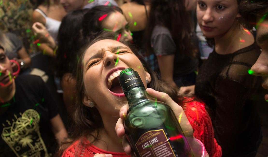 Closeup shot of a woman drinking shots out of a bottle at a party.