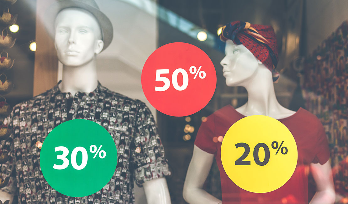 Mannequins in store window with 20%, 30% and 50% sale signs