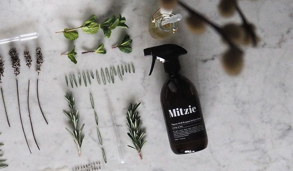 spray bottle laying alongside herbs on a white granite countertop