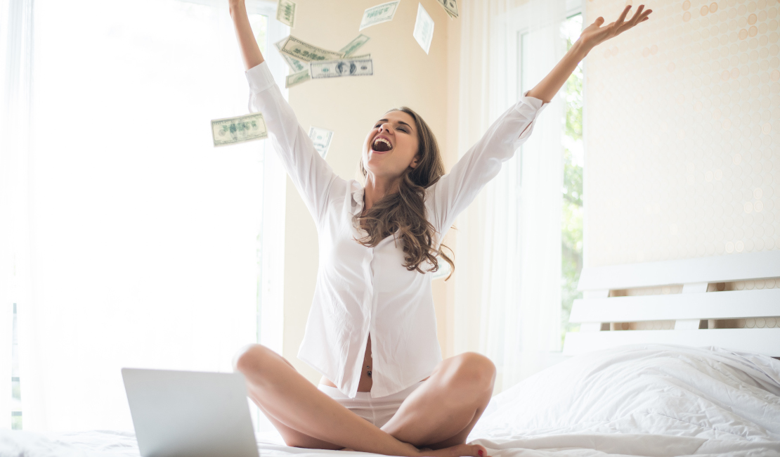 Woman on bed, tossing money in the air while she is buying a bed online.